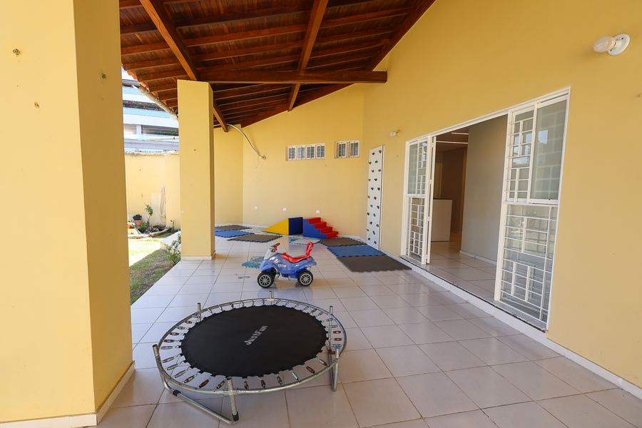 Varanda coberta da área externa com cama elástica e parede de escalada
