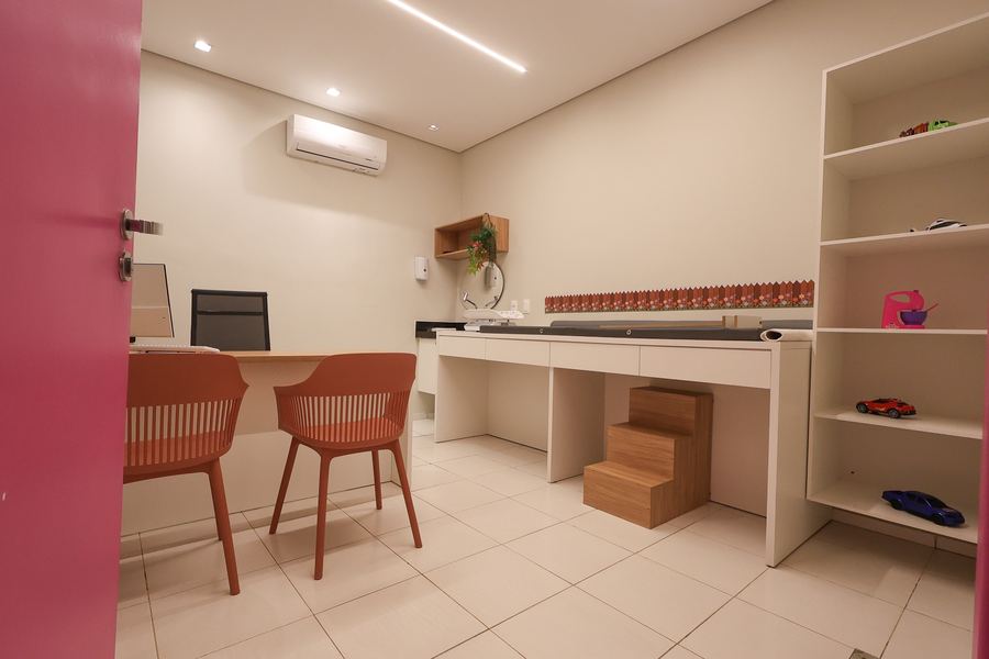 Consultório 02 com porta rosa, estante branca e bancada