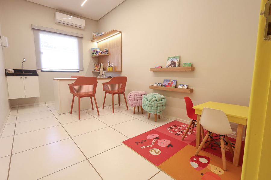 Sala de Psicologia com porta amarela, mesa infantil, tapete e poltronas