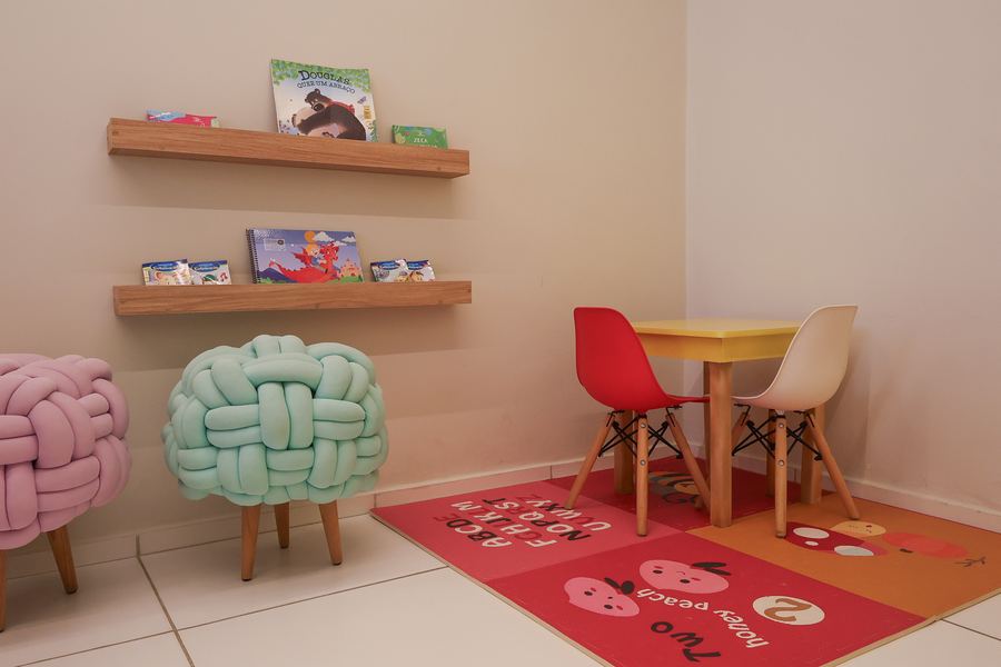 Canto de leitura da sala de Psicologia com prateleiras de livros e puffs coloridos