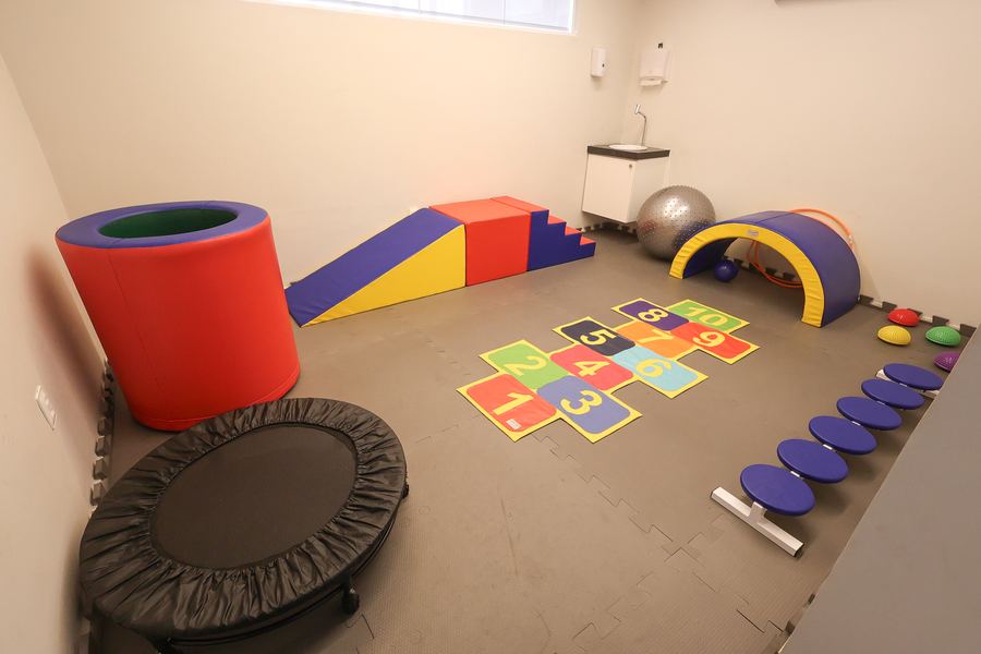 Sala de psicomotricidade com cama elástica, módulos de espuma e tapete de amarelinha