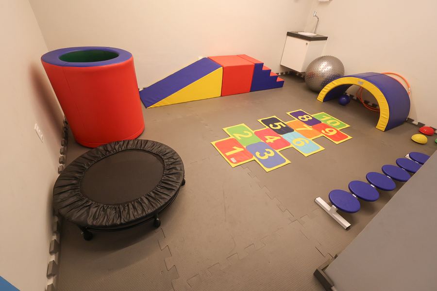 Sala de psicomotricidade com módulos de espuma, bola suíça e arcos
