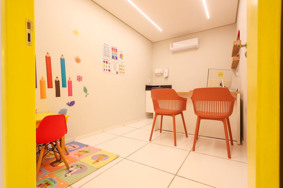 Sala de Psicopedagogia com porta amarela, parede de lápis coloridos e mesa infantil