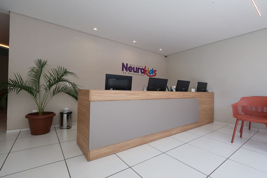 Balcão da recepção com estações de computador e logotipo na parede